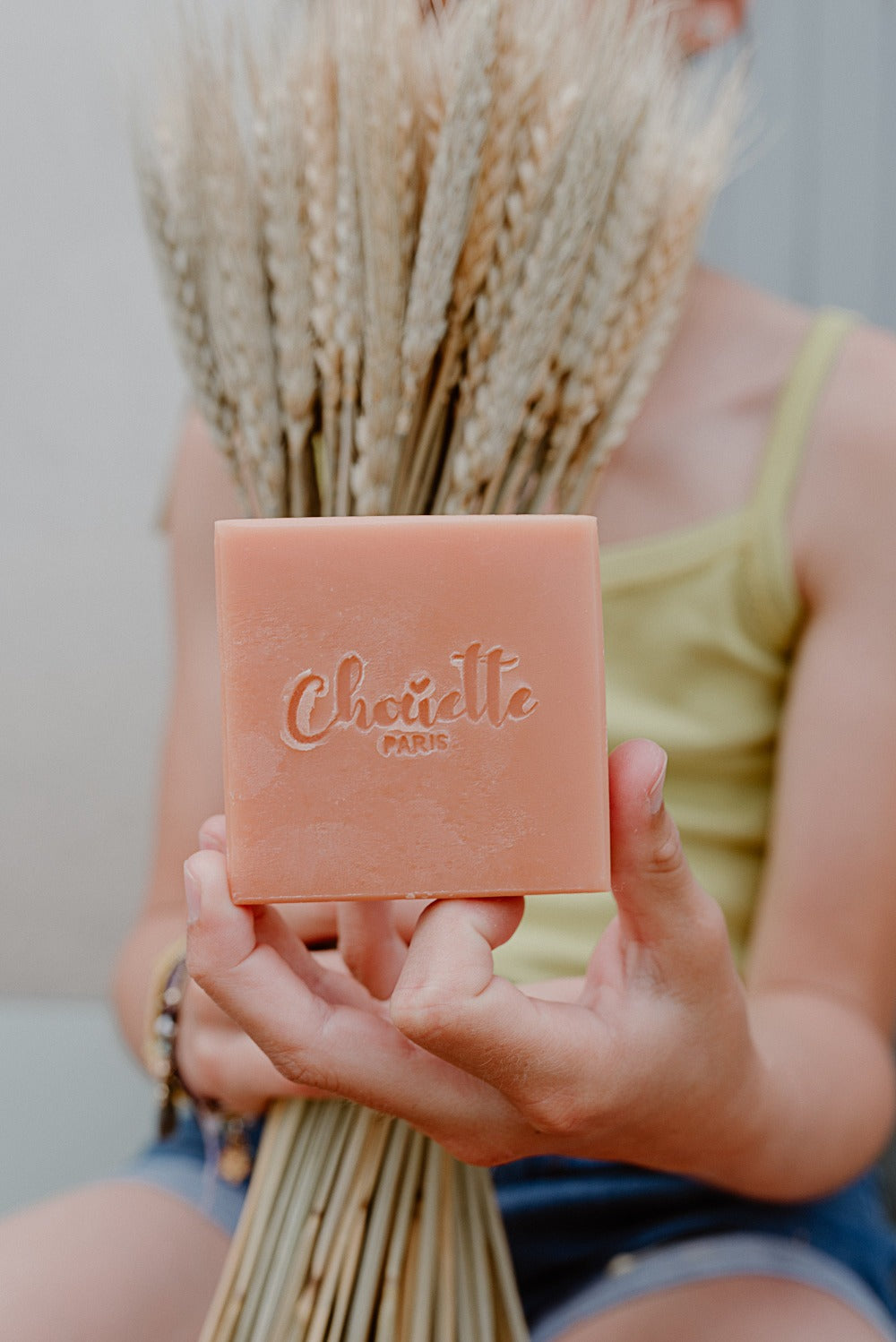 Savon carré orange avec Chouette gravé , tenu dans ma main d'une pette fille et gerbe de blé en arrière plan