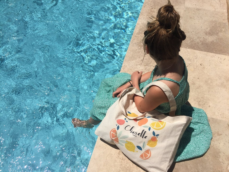 jeune fille au bord d'une piscine, les pieds dans l eau avec le sac Chouette , soins de cosmétiques enfants